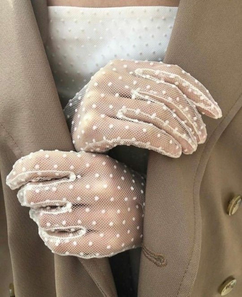 Pu&ograve; includere: Un paio di guanti in rete bianca a pois. I guanti sono delicati e femminili, con un motivo sottile di piccoli pois bianchi.