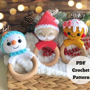 May include: Three crocheted Christmas-themed baby teethers: a snowman, Santa Claus, and a gingerbread person. Each teether is attached to a wooden ring.