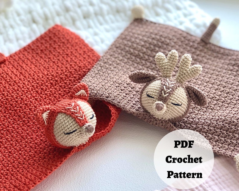 Peut inclure: Deux couvertures pour b&eacute;b&eacute; en crochet avec des applications d'animaux. Une couverture est orange avec une application de renard et l'autre est marron avec une application de renne. Les couvertures sont sur une surface blanche avec le texte "PDF Crochet Pattern" dans un cercle.