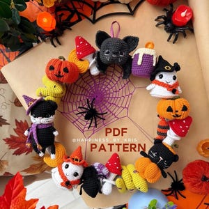 Può includere: Una ghirlanda circolare all'uncinetto con varie figure a tema Halloween, tra cui un pipistrello nero, fantasmi, zucche, funghi rossi e bianchi e gatti neri. Il centro mostra una ragnatela viola all'uncinetto con il testo PDF @HAPPINESS_BY_KRIS PATTERN.