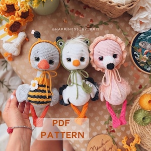 Op de afbeelding: Drie gehaakte knuffels bestaande uit een vogel in bijenkostuum, een in een kikkerkostuum en een in een flamingo-ontwerp. Het speelgoed heeft ronde koppen, oranje snavels en bungelende poten. De tekst PDF PATTERN is in het midden zichtbaar.