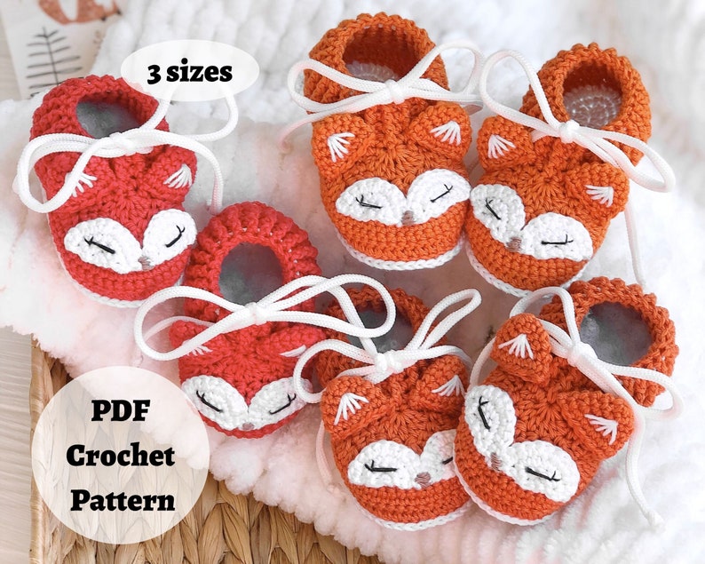 May include: Crochet pattern for fox baby booties in three sizes. The booties are orange and red with white accents and laces. The pattern is available as a PDF download.