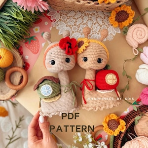 Peut inclure: Deux escargots en crochet avec de grands yeux noirs et des joues roses. L'un porte une coquille en forme de maison verte et un bandeau coquelicot, l'autre une coquille pomme rouge et un bandeau tournesol. Le texte indique PDF PATTERN.
