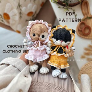 May include: Two crocheted cat dolls wearing dresses and bonnets. One cat is tan with a pink outfit, and the other is black and white with a yellow outfit. The image includes the text "CROCHET CLOTHING SET" and "PDF PATTERN".