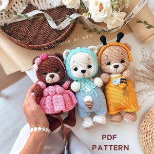 Può includere: Tre giocattoli amigurumi a forma di orsacchiotto all'uncinetto. Uno indossa un vestito rosa con un fiore sulla testa, uno indossa un completo blu e bianco con un cono gelato e uno indossa un completo giallo e nero con un'ape sul petto. Il testo "PDF PATTERN" è scritto sotto gli orsi.