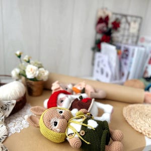 May include: A crocheted bunny toy wearing a green and white outfit and a yellow hat. The bunny is lying on a brown surface.
