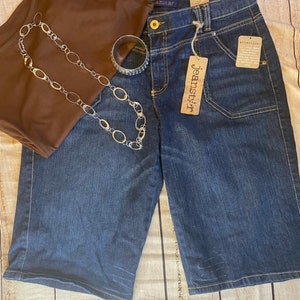 May include: Dark blue denim shorts with a brown tank top, a silver chain necklace, and a silver bracelet. The shorts have a brown tag that says "Jeanstarr" and "attentional".