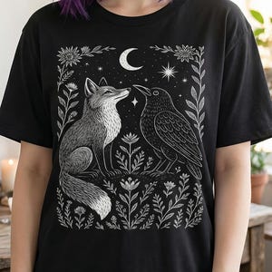 Witchy fox and crow tshirt with a crescent moon and floral border. Unisex cotton tee with a crew neck. White ink on a black t-shirt. Dark cottagecore clothing.