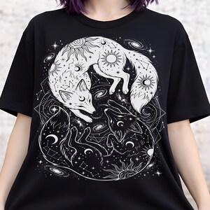 Black and white fox shirt featuring two curled foxes in a yin yang formation with sun, moon, and constellation details in white ink.