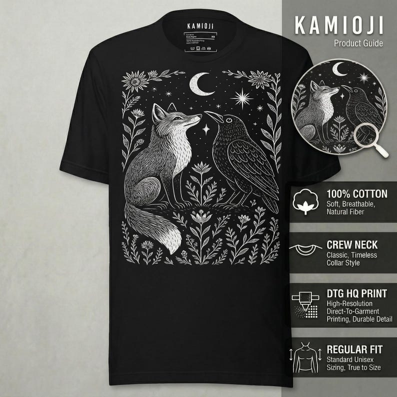 Puede incluir: Camiseta negra de cuello redondo con una ilustraci&oacute;n blanca de un zorro y un cuervo enfrentados, rodeados de flores y estrellas. La camiseta tiene el texto "KAMIOJI" en la parte superior. Impresa en algod&oacute;n.