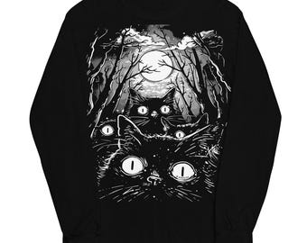 May include: Black long-sleeve shirt featuring a spooky illustration of several black cats with glowing eyes in a moonlit forest. The design is in black and white, creating a striking contrast. The shirt is a comfortable, casual wear.