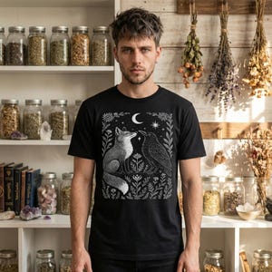Fox and crow shirt with celestial accents, blending gothic nature and folk art styles. Unisex fit, 100% cotton t-shirt, crew neck.