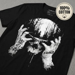 K&ouml;nnte beinhalten: Schwarzes T-Shirt mit einem Totenkopf-Design und einer Waldszene. Der Sch&auml;del wird von zwei H&auml;nden gehalten, mit japanischem Text auf dem linken Arm und dem Wort "KAMIOJI" auf dem rechten. Ein rundes Etikett zeigt "100% COTTON".