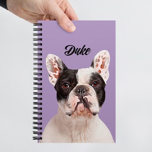 May include: A purple spiral bound notebook with a white and black French bulldog illustration and the name "Duke" printed in black.