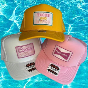May include: Three trucker hats with foam fronts and mesh backs. One is yellow with "TACOS AND MYRCS" on the front, another is white with "Coors", and the third is pink with "Babewelser". Each hat has a "OTTO" label.