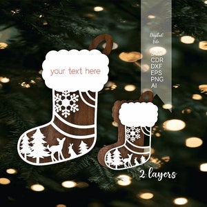 May include: Two wooden Christmas stocking ornaments with a white snowflake design and a deer and rabbit in a forest scene. The larger stocking has a blank space for text that says "your text here".