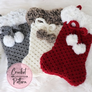 May include: Three crocheted Christmas stockings with faux fur trim. The stockings are gray, white, and red. Each stocking has a pom-pom on the top.