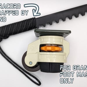 May include: A beige and black swivel caster with a black paracord handle wrapped around it. The caster is labeled "Model 360" and the handle has the text "PARACORD WRAPPED BY HAND" and "FOR BRAND: FOOT MASTER ONLY".