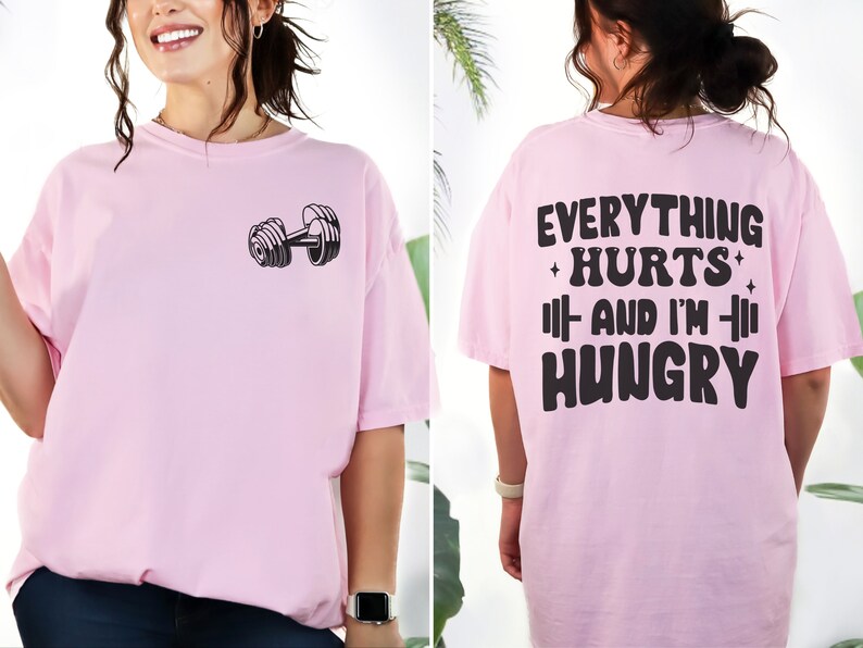 May include: Pink t-shirt with a dumbbell graphic on the front and the text "Everything Hurts And I'm Hungry" on the back.