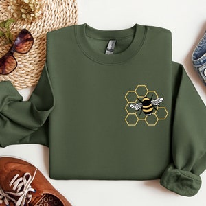 May include: A green sweatshirt with a yellow and black bee graphic on a honeycomb design.