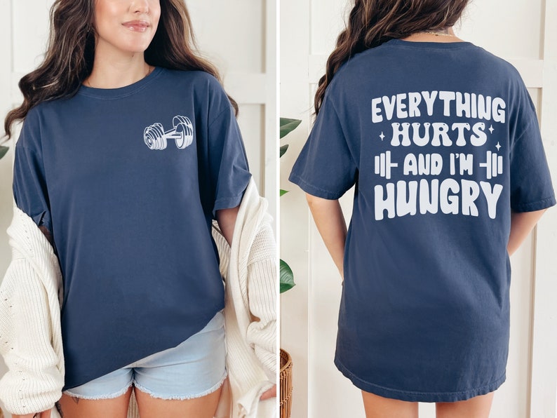 May include: A navy blue t-shirt with a white dumbbell graphic on the front and the text "Everything Hurts + And I'm + Hungry" on the back.