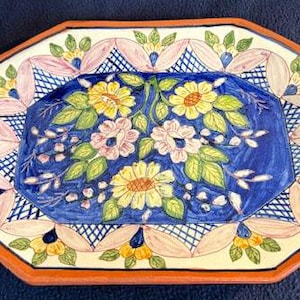 May include: Octagonal ceramic serving platter with a blue background and a floral design in shades of yellow, pink, and green. The platter has a white border with a pink and white lattice pattern.