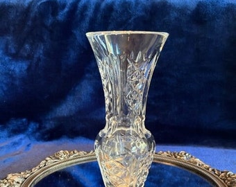 May include: A clear glass vase with a cut crystal design. The vase is sitting on a silver tray with a mirrored surface.