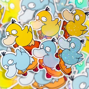May include: A set of six colorful stickers featuring a cartoon duck character riding a skateboard. The stickers are printed on a clear background with a holographic finish. The duck character is depicted in various poses and colors, including yellow, blue, and green.