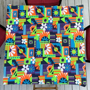 Peut inclure: Une nappe géométrique colorée avec un motif répétitif de fleurs, de carrés et de triangles dans des tons d'orange, de vert, de bleu, de violet et de blanc.