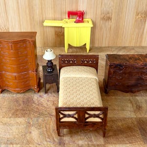 Puede incluir: Un conjunto de muebles de madera en miniatura, que incluye una cómoda, una cama, una mesita de noche y una mesa pequeña. Los muebles están pintados en un acabado de madera oscura y tienen detalles intrincados. La cama tiene un edredón estampado beige.