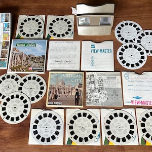 Könnte beinhalten: Ein Vintage View-Master-Betrachter und eine Sammlung von 3D-Rollen mit Bildern von Rom und dem Vatikan. Die Rollen befinden sich in ihrer Originalverpackung und beinhalten einen Reiseführer für den Vatikan.