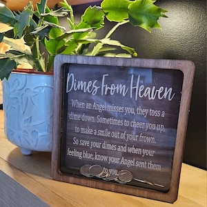 May include: A wooden box with a glass front that says "Dimes From Heaven" and has a quote about angels sending dimes when they miss you. The box is filled with dimes.