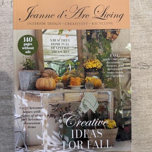 May include: The Jeanne d'Arc Living magazine cover features a light orange header with the title and text Interior Design - Creativity - Recycling. The main image shows a rustic wooden table with pumpkins, flowers, and a green checkered cloth.