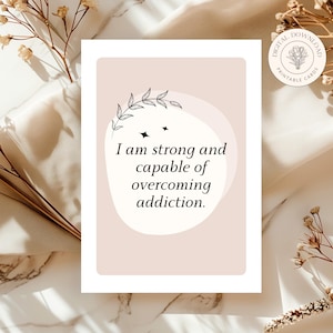 May include: A pink and white affirmation card with a floral design and the text "I am strong and capable of overcoming addiction."