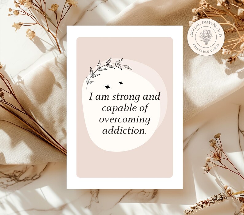 May include: A pink and white affirmation card with a floral design and the text "I am strong and capable of overcoming addiction."