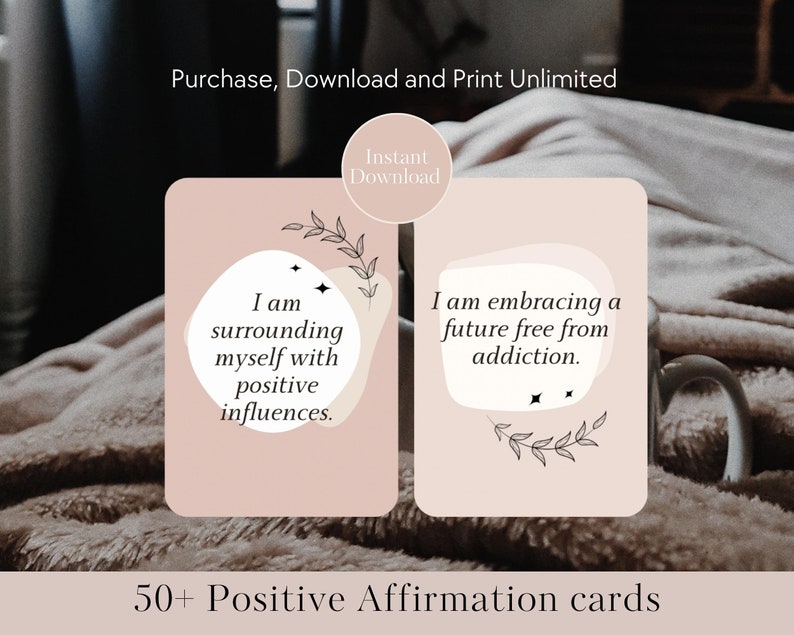 May include: Two pink affirmation cards with black text and illustrations of leaves. The card on the left reads "I am surrounding myself with positive influences." The card on the right reads "I am embracing a future free from addiction." The cards are on a brown fuzzy surface. 50+ Positive Affirmation cards.