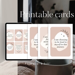 May include: Printable cards with positive affirmations on a pink background. The cards feature a simple design with black text and a small floral illustration. The text on the cards includes phrases like "I am making progress, no matter how small" and "I am choosing to be kind to myself on this journey."