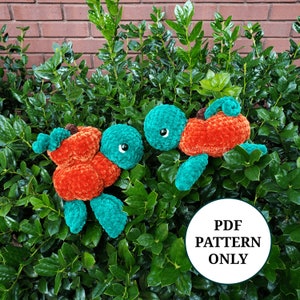 May include: Two crocheted turtle amigurumi toys with orange and teal bodies. The turtles are sitting on a bed of green leaves. The text "PDF PATTERN ONLY" is visible in the image.