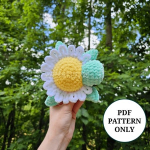 May include: Crochet pattern for a daisy flower with a green turtle shell. The pattern is available as a PDF download.