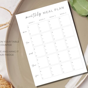 May include: A printable monthly meal planner with a simple design. The planner is divided into four weeks and includes spaces for breakfast, lunch, and dinner for each day of the week. The text "Keep it on your table or counter" and "Laminate and hang it on your fridge" is included.