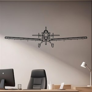 Könnte beinhalten: Ein Wandkunstwerk aus schwarzem Metall, das ein Flugzeug darstellt. Das Flugzeug ist in einem minimalistischen Stil dargestellt, mit detaillierten Flügeln, Propeller und Fahrwerk. Das Kunstwerk ist an einer neutralfarbenen Wand in einem Büroumfeld angebracht.