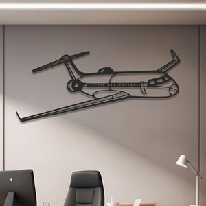 May include: A black metal airplane wall art piece. The artwork depicts a detailed outline of a jet, including wings, tail, and fuselage. The art is mounted on a light gray wall in an office setting.