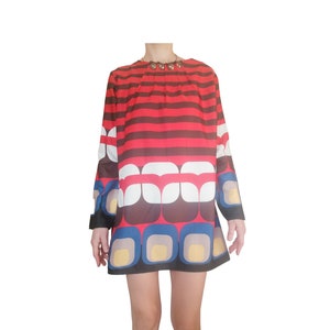 May include: A red, white, and blue geometric patterned mini dress with long sleeves.