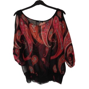 Puede incluir: Top negro transparente con estampado paisley rojo y naranja. El top tiene cuello redondo y mangas cortas.