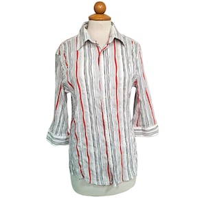 May include: A button-down shirt with a white background and vertical stripes in red and black. The shirt has three-quarter sleeves and a collared neckline. The shirt is displayed on a mannequin.