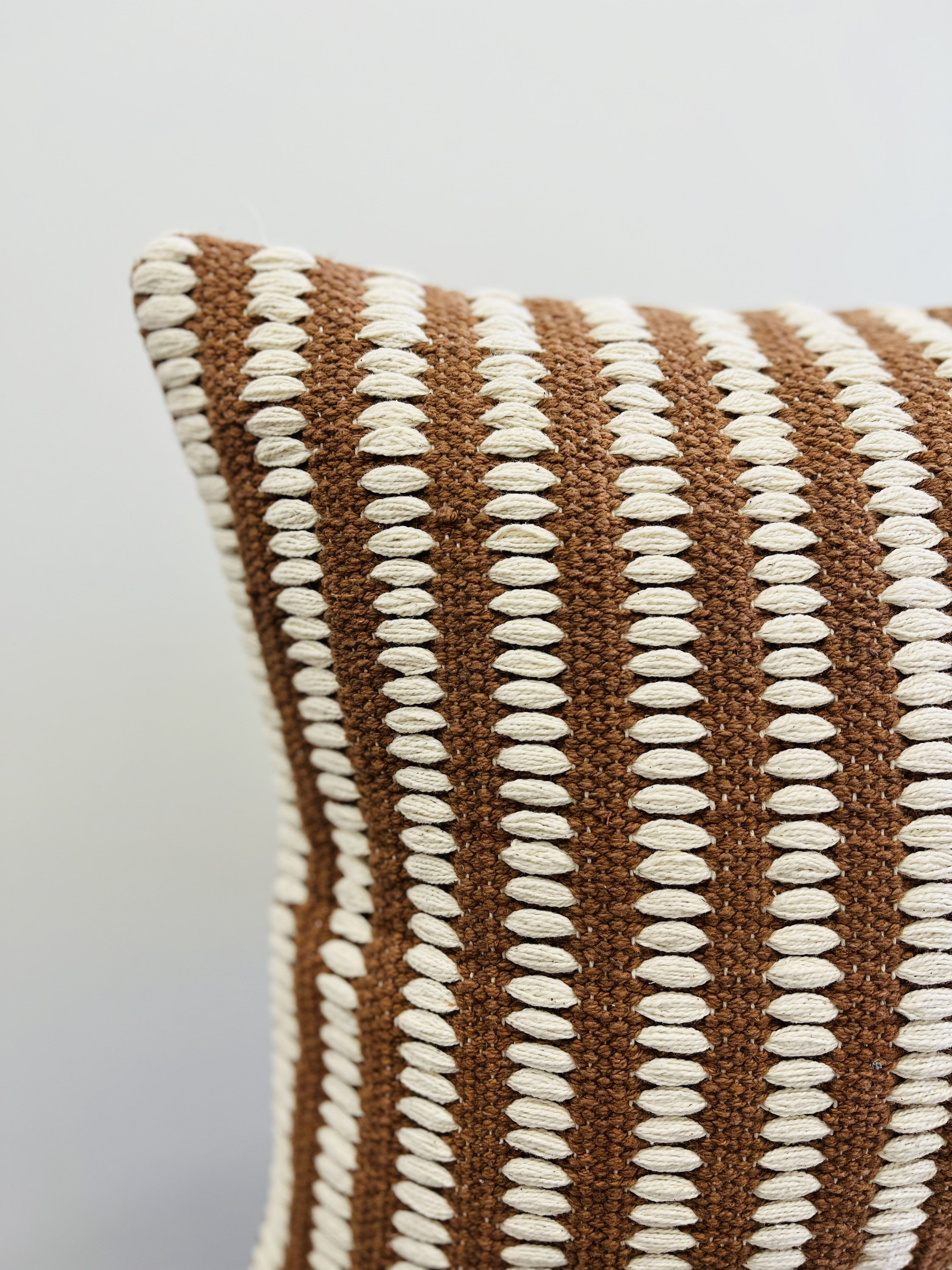 May include: Brown and white striped throw pillow with a textured woven design.