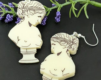 May include: Ivory-colored earrings featuring a classical bust design with dark brown line art. The earrings depict a woman's bust with detailed hair and facial features. The earrings have silver-colored hooks.