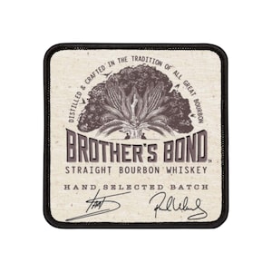 Puede incluir: Un parche marrón y blanco con el texto "DISTILLED & CRAFTED IN THE TRADITION OF ALL GREAT BOURBON" alrededor de un dibujo de mazorcas de maíz. El texto "BROTHER'S BOND STRAIGHT BOURBON WHISKEY" está debajo del dibujo. El texto "HAND SELECTED BATCH" está debajo del nombre del whisky. Los textos "TH" y "R.W. Weller" están firmados debajo del texto.