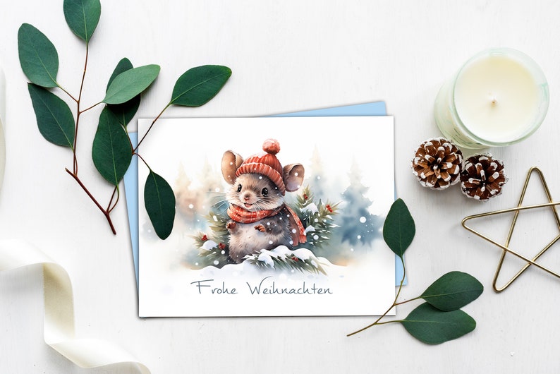 K&ouml;nnte beinhalten: Eine Weihnachtskarte in Aquarelltechnik mit einer niedlichen Maus, die einen roten Hut und Schal tr&auml;gt und in einem verschneiten Wald steht. Die Karte tr&auml;gt den Schriftzug "Frohe Weihnachten".