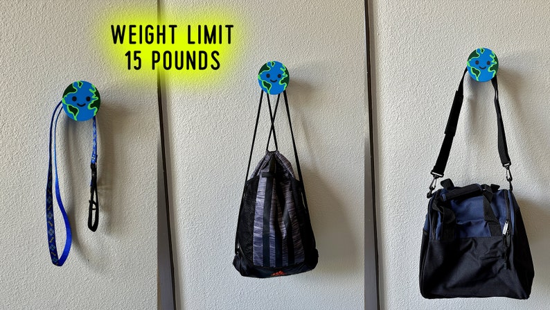May include: Three wall hooks with a globe design, each holding a different item. The hooks are holding a blue and black dog leash, a black and grey drawstring bag, and a black and blue duffel bag. Text above reads "WEIGHT LIMIT 15 POUNDS."